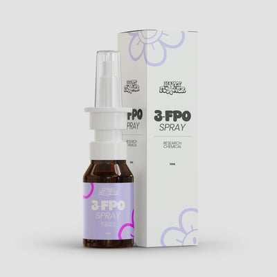 Braune 10-ml-Sprühflasche mit weißem Nasenaufsatz und transparenter Schutzkappe vor der passenden weißen Produktverpackung. Flasche und Karton tragen das Happy-Flower-Logo sowie die Aufschrift „3-FPO Spray – Research Chemical“ und lilafarbene Blütenelemente.